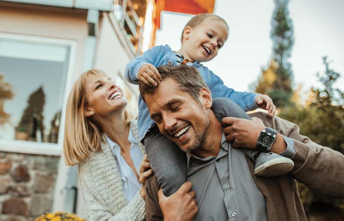 Family of three smiling outside