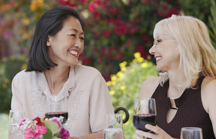 Two women smiling while drinking wine